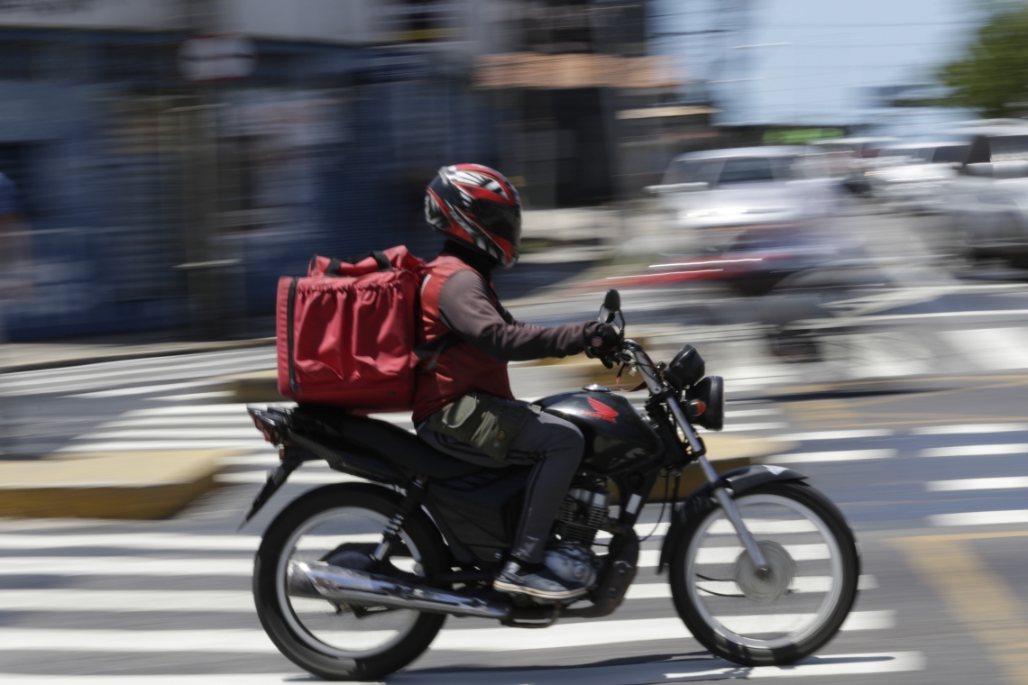 Homem anda de moto com mochila de entrega de lanches