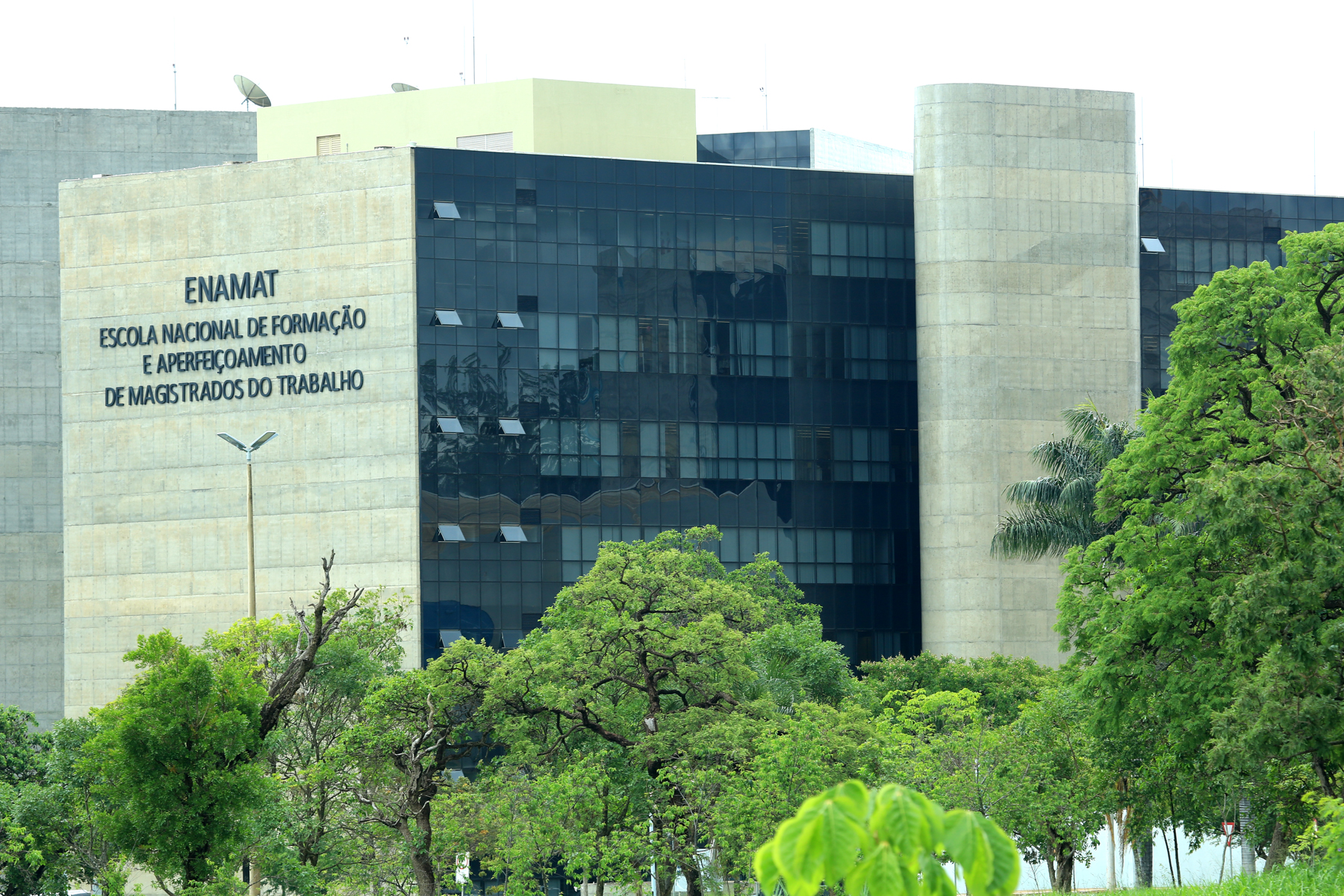 Fachada do edifício-sede do TST, CSJT e Enamat. Nome Enamat em letras caixas pretas na fachada de concreto do prédio.