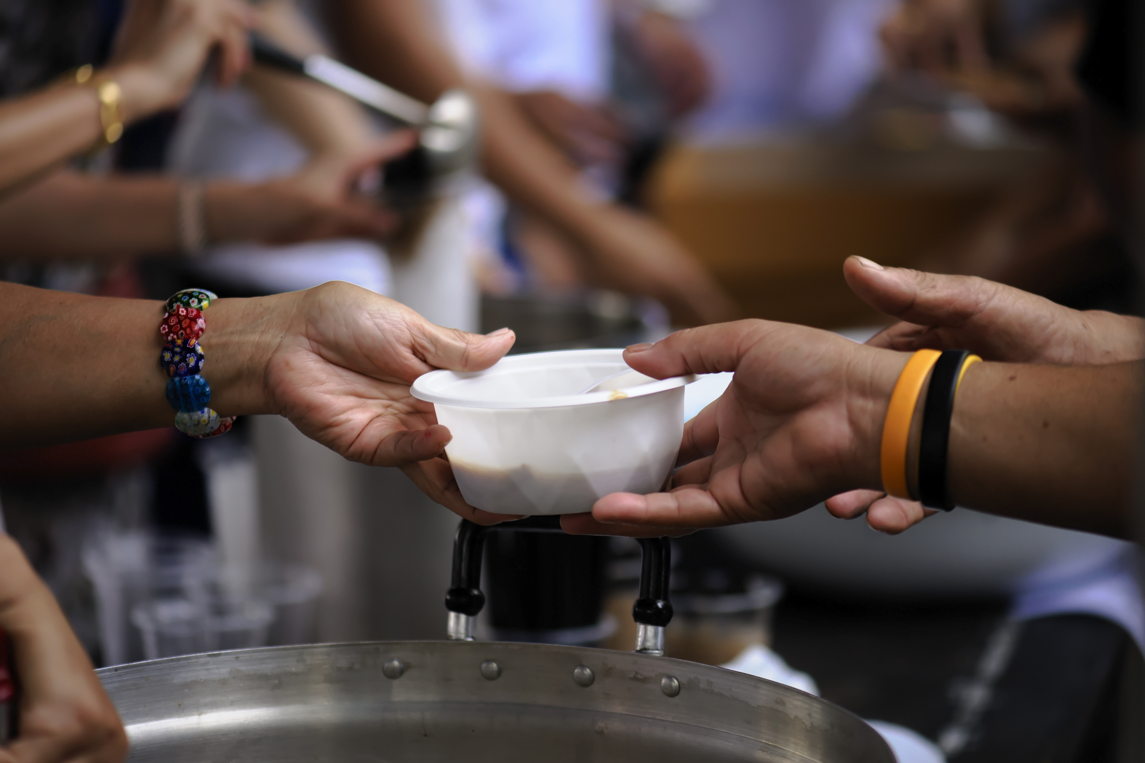 Imagem mostra vasilha com comida sendo servida para uma pessoa