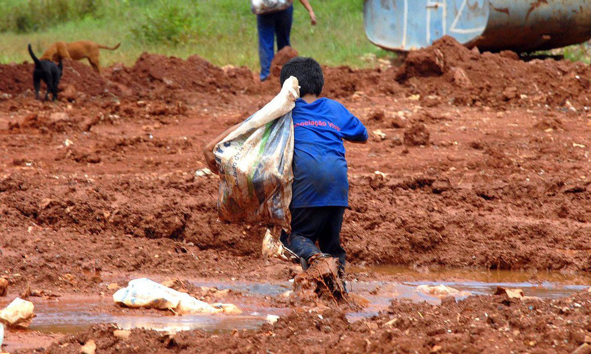 Criança com os pés na lama coletando lixo em lixão - Foto: Marcello Casal/Agência Brasil