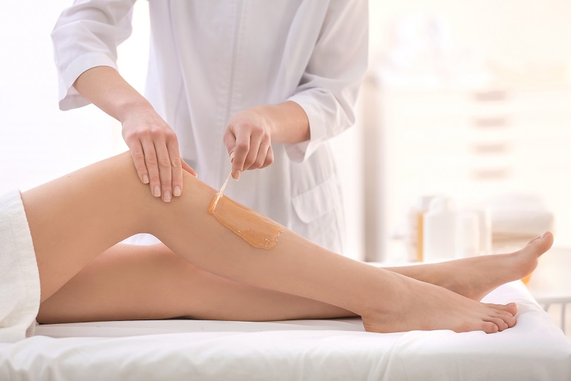 Imagem: mulher depilando perna de cliente