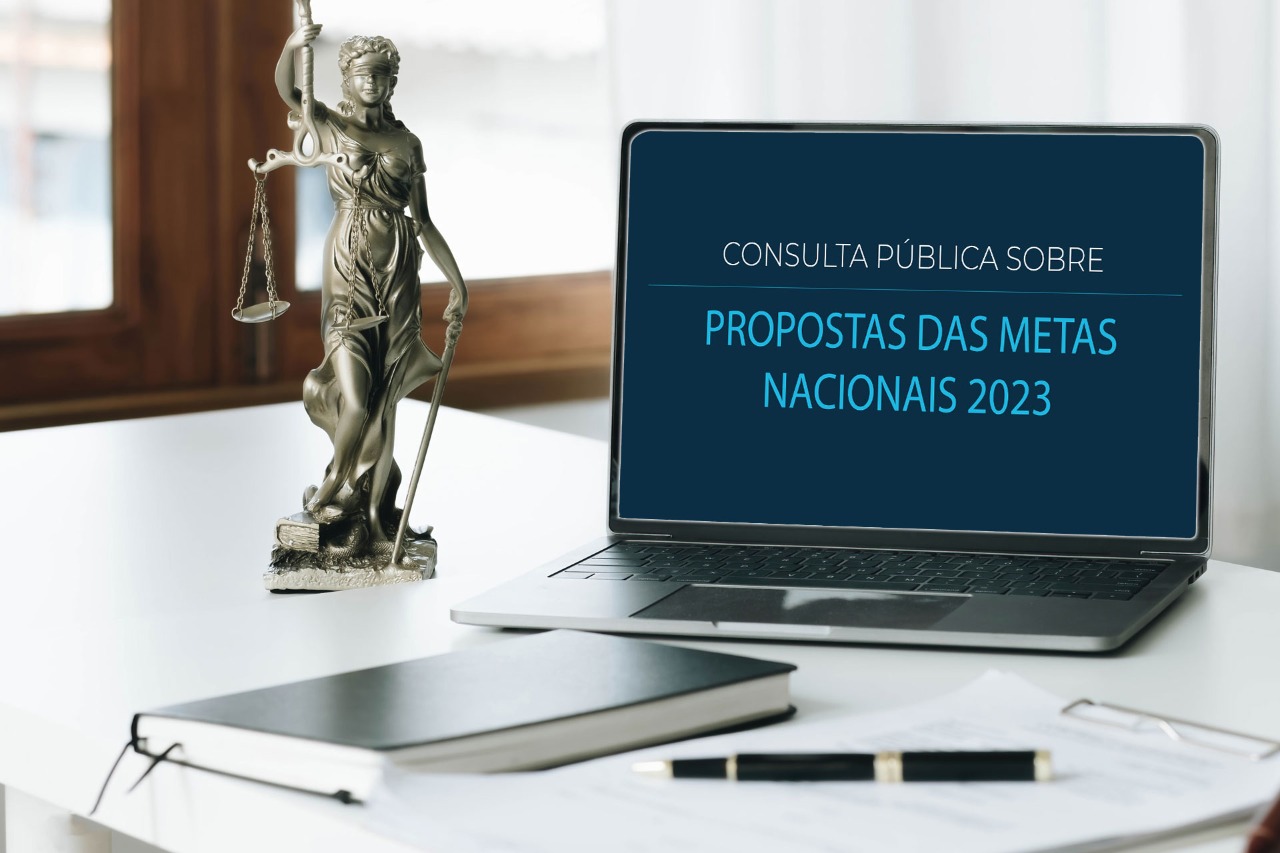 Mesa com estatua da justiça e notebook. Na tela está escrito Consulta Pública Sobre Propostas das Metas Nacionais 2023