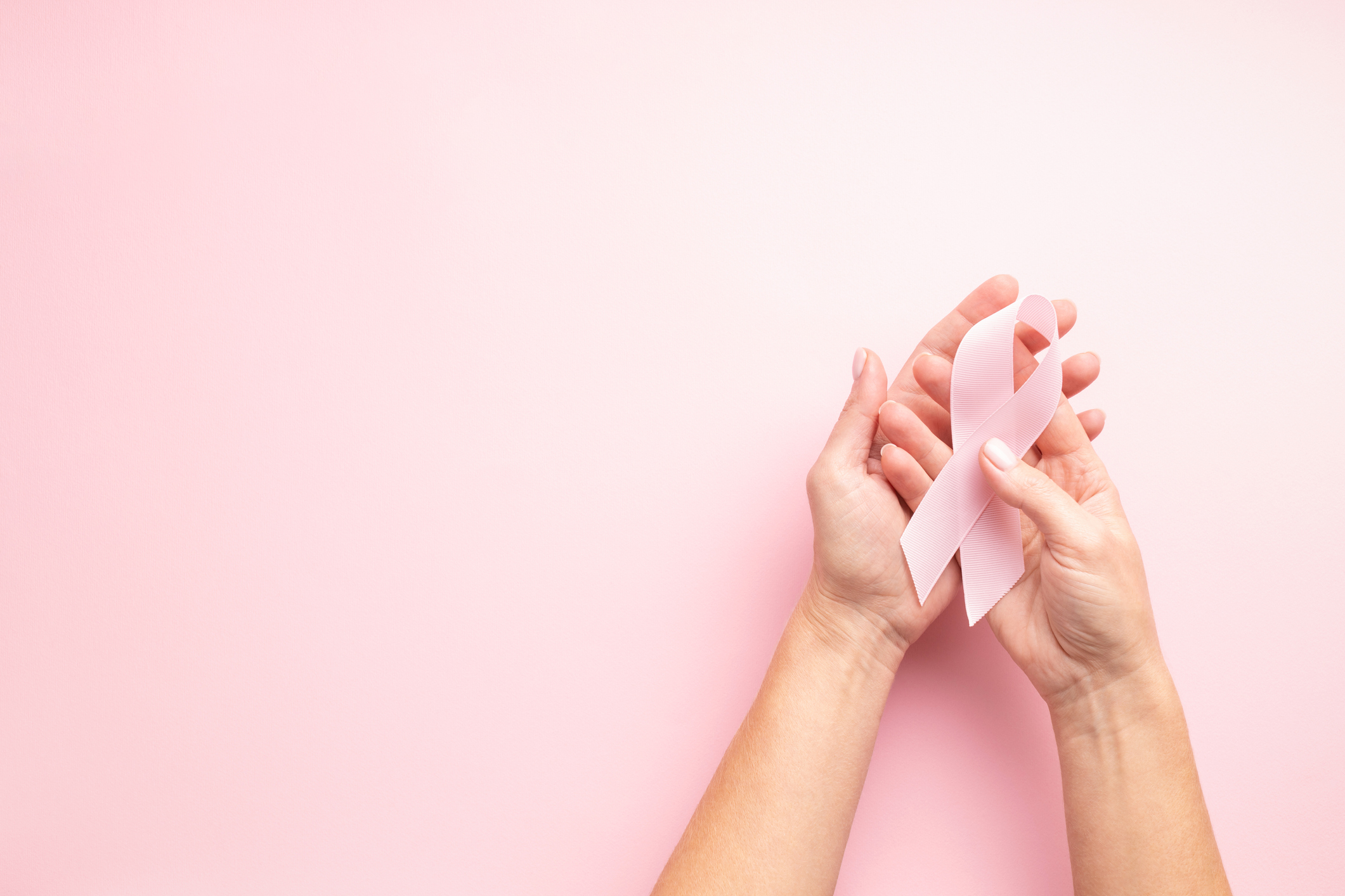 Imagem: pessoa segurando símbolo da prevenção ao câncer de mama