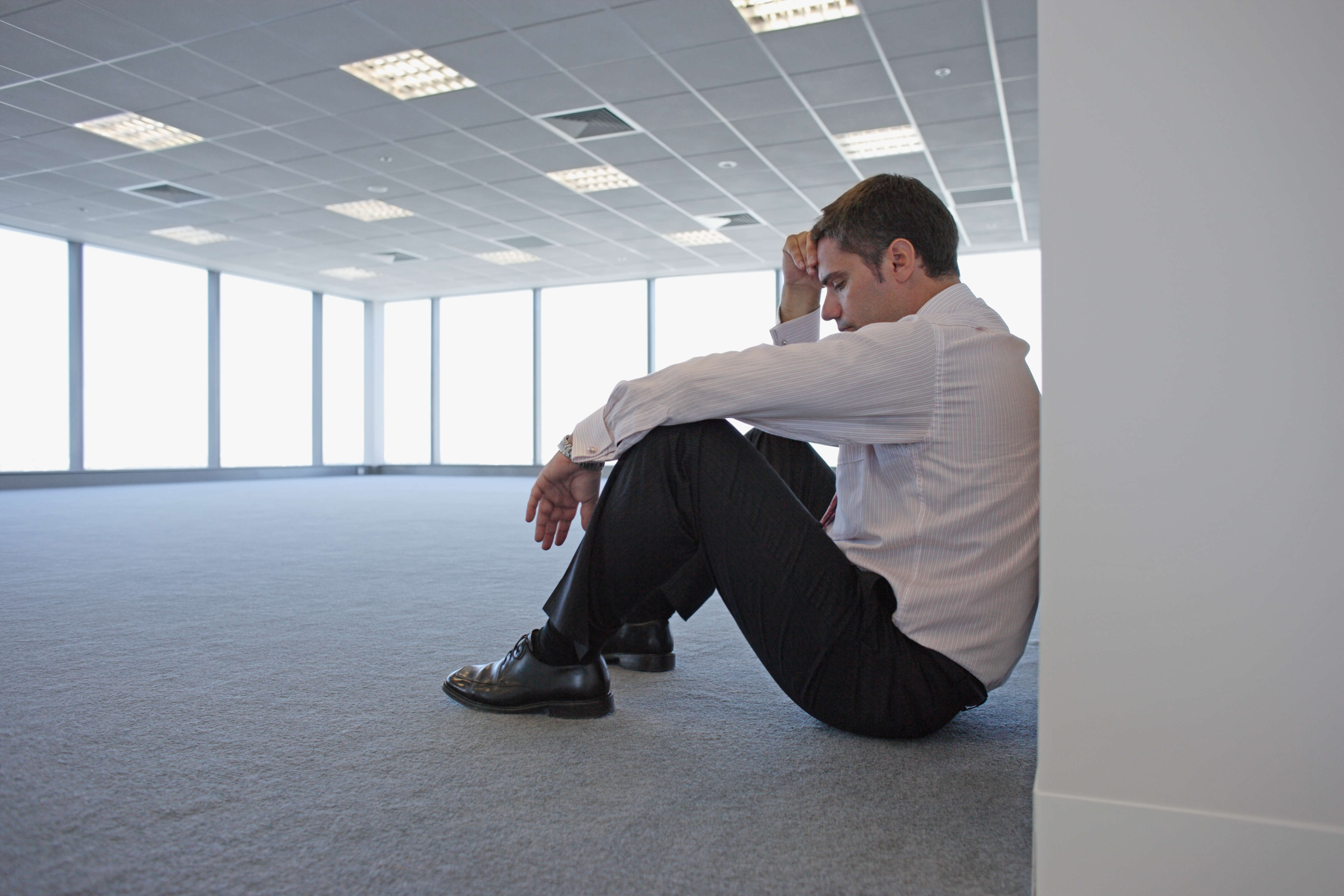 Imagem: homem cabisbaixo sentado no chão