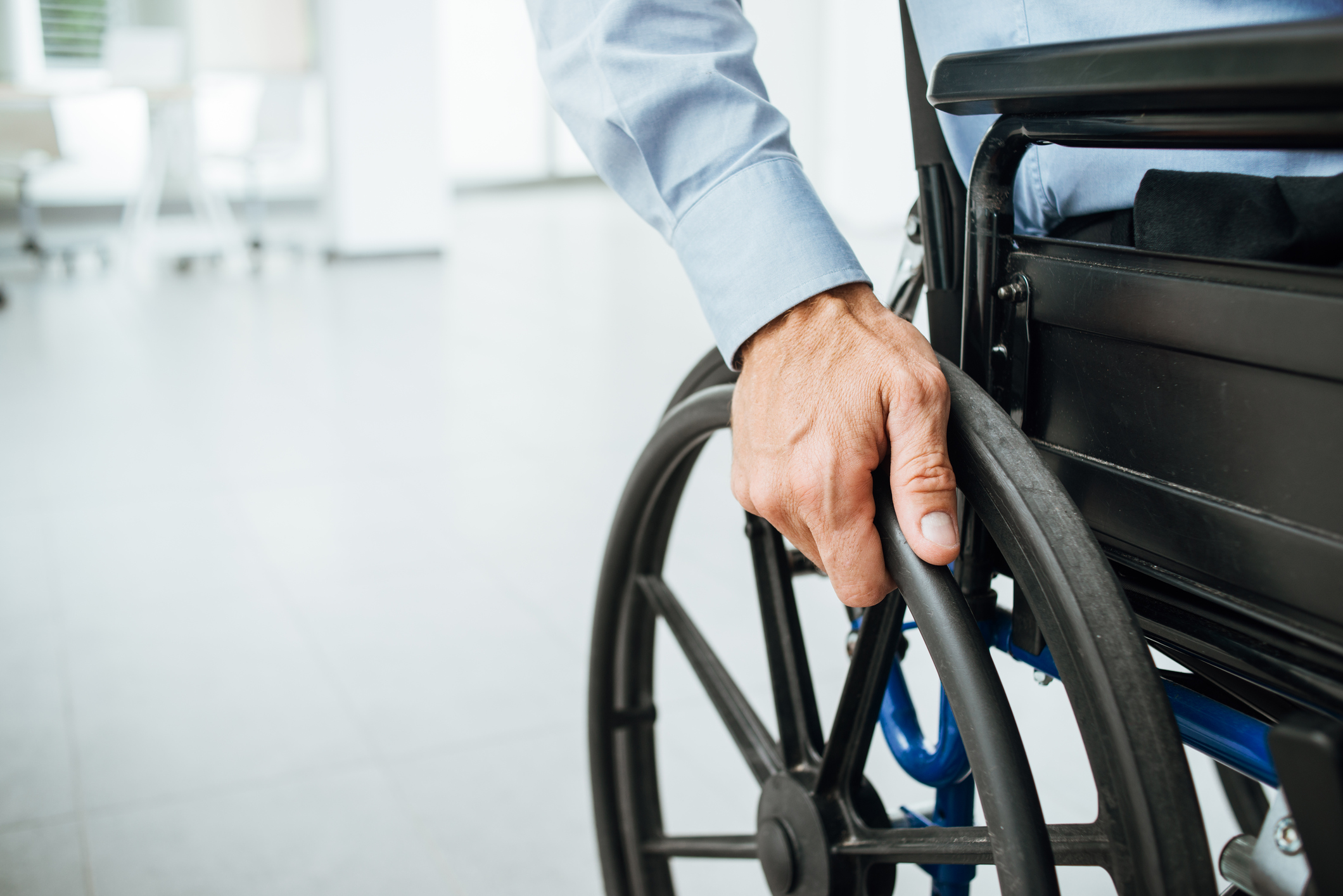Imagem: detalhe de pessoa segurando cadeira de rodas 