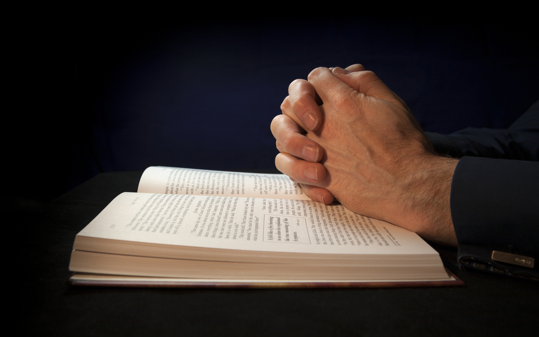 Imagem: mãos sobre bíblia, em posição de reza