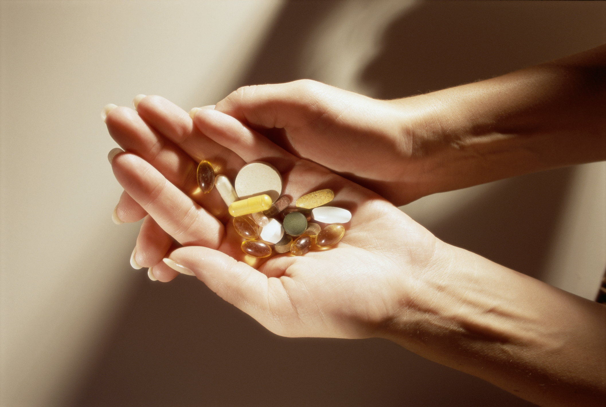 Imagem: pessoa segurando diversos comprimidos nas mãos 