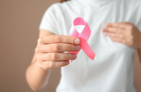 Imagem: mulher segurando símbolo do combate ao câncer de mama