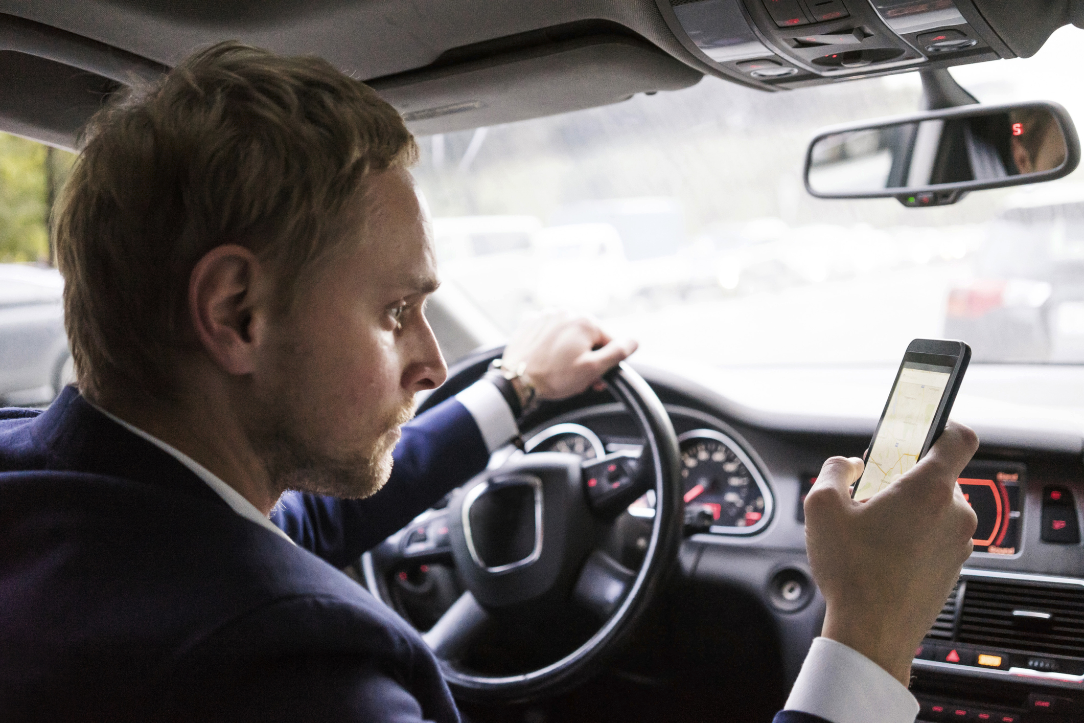 Imagem: homem olhando para celular dentro de carro