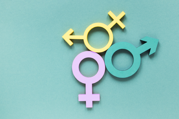 Fundo verde com símbolos de gêneros nas cores amarela, rosa e verde. (Foto: Freepik)