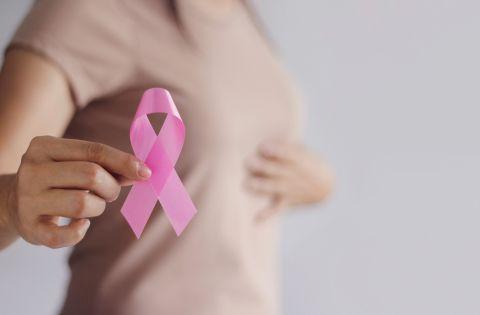 Na imagem, mulher segurando laço cor de rosa, símbolo da luta contra o cancêr de mama