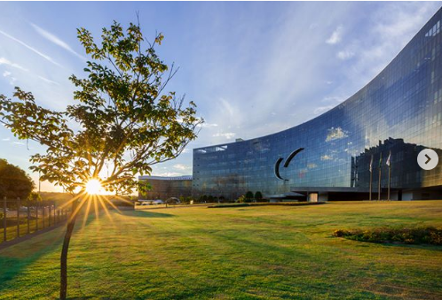 Edifício-sede do TST com ipê em primeiro plano e sol ao fundo
