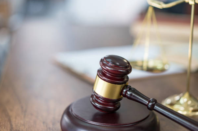 Malhete sobre a mesa, com balança ao fundo.