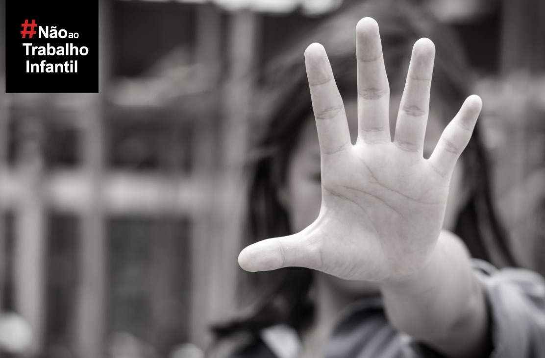 Menina com a mão espalmada em primeiro plano e, ao lado, a hashtag #NãoaoTrabalhoInfantil