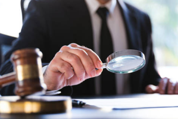 Homem de terno segurando lupa sobre documentos