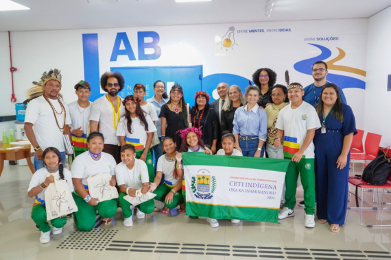 Fotografia com a presença de diversas pessoas ao redor da bandeira ''Ceti Indígena'' representando a participação dos estudantes indígenas. 