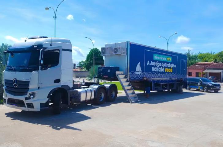 Foto colorida mostra um caminhão com uma carreta azul da Justiça do Trabalho, levando atendimento móvel e a legenda ''A Justiça do Trabalho vai até você''.