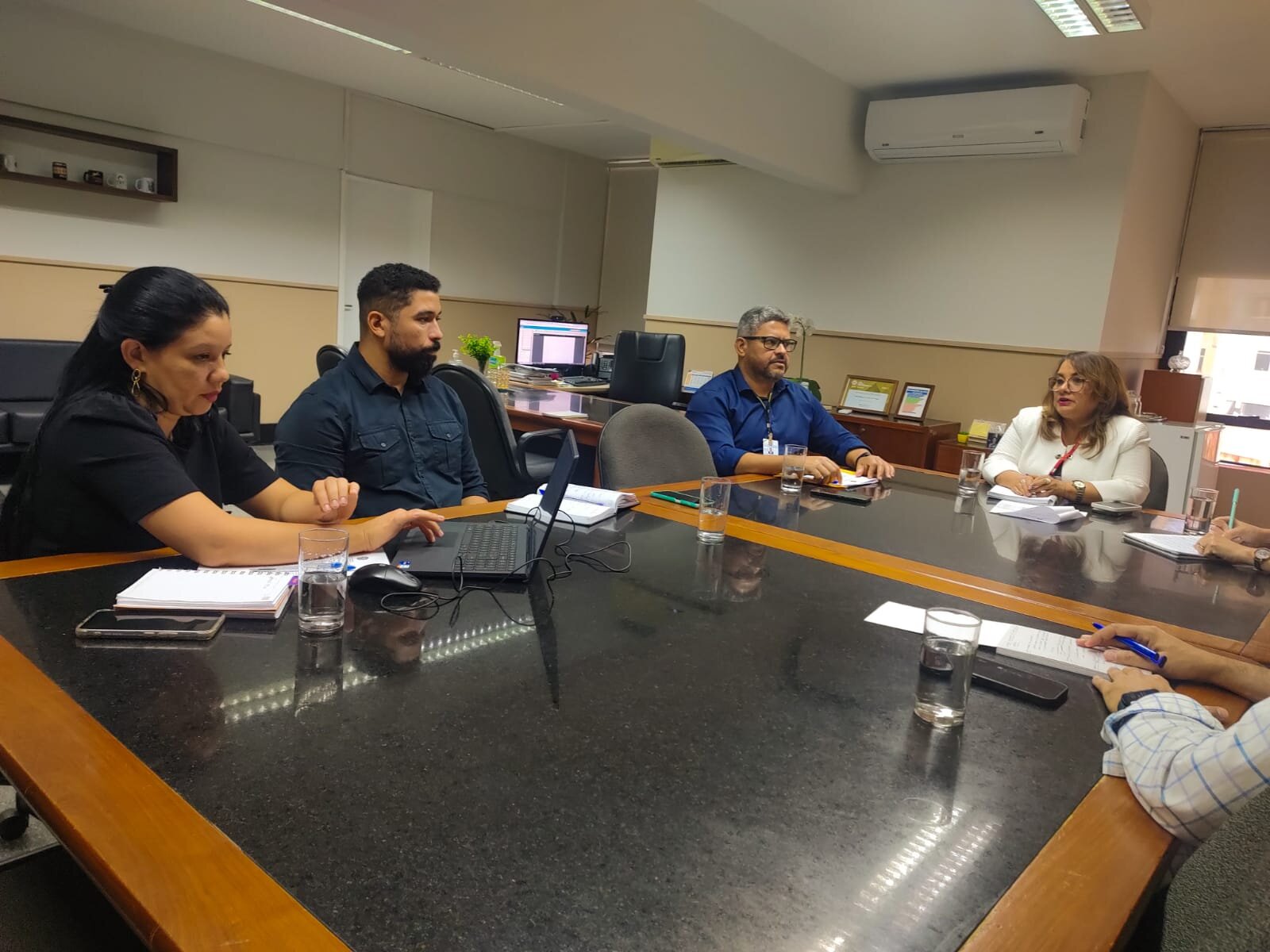 Fotografia mostra a Diretora-Geral do TRT-16 (MA) sentada à mesa com 3 pessoas