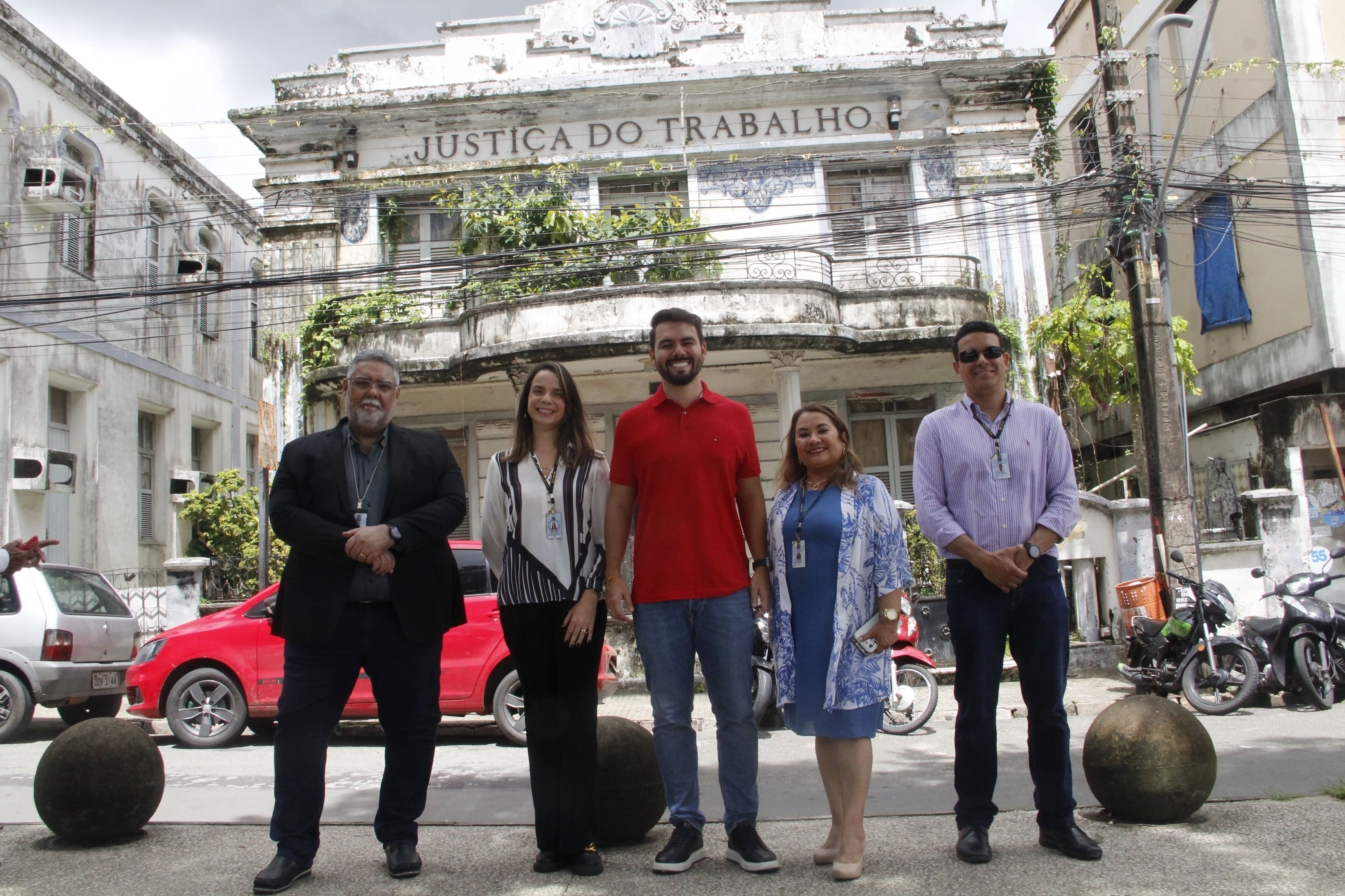 Foto mostra a diretora-geral do TRT16, Fernanda Muniz, o secretário de Estado da Cultura, Yuri Arruda, o secretário de orçamento e finanças do TRT-16, Júlio César, a chefe da DIVENG, Andréa Saldanha, e do servidor Marcelo Alencar. Ambos estão posicionados em frente ao prédio histórico da Justiça do Trabalho, na praça Deodoro em São Luis.
