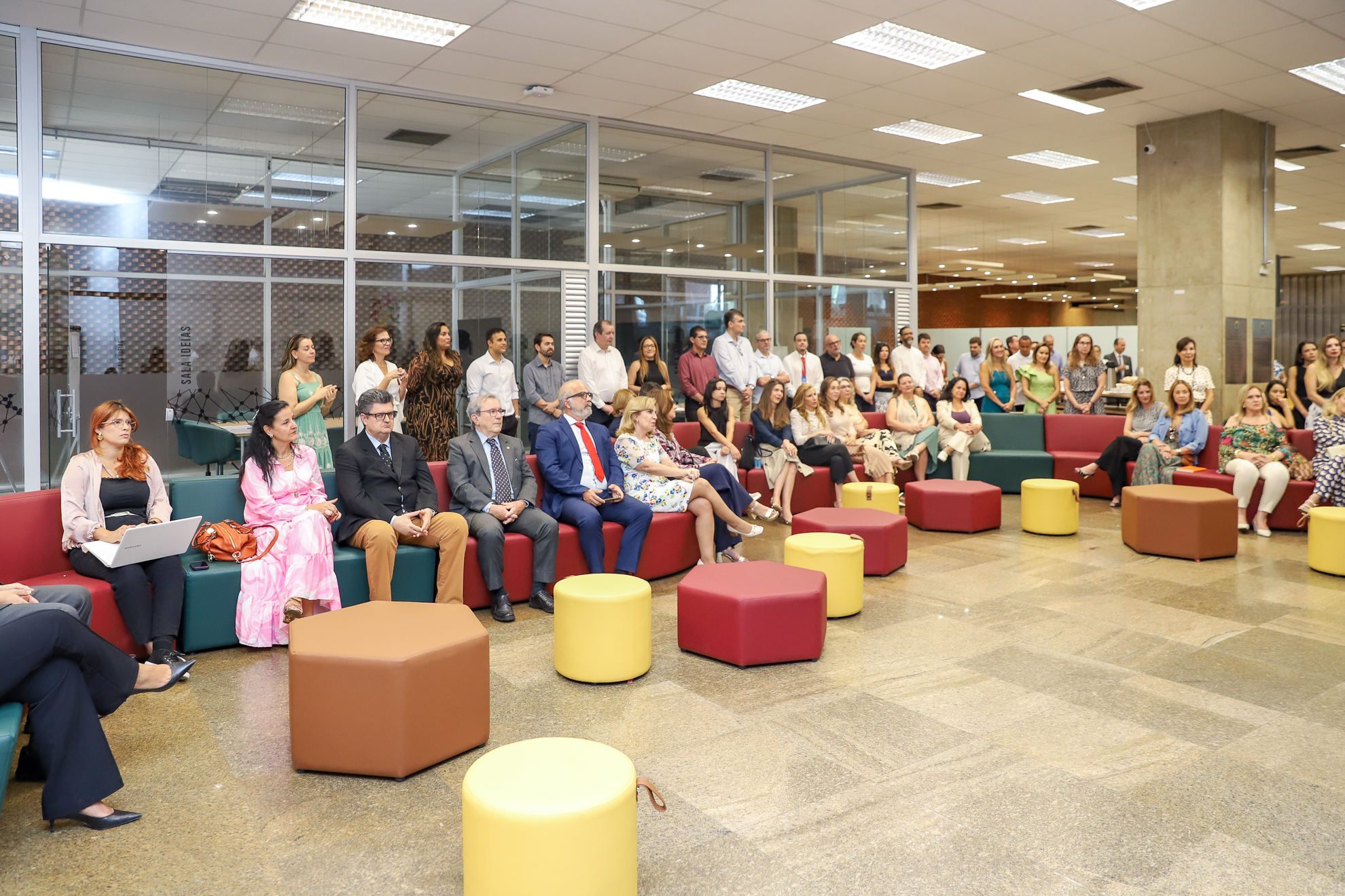 Fotografia com diversas pessoas presentes, uma parte sentada e outra em pé. 