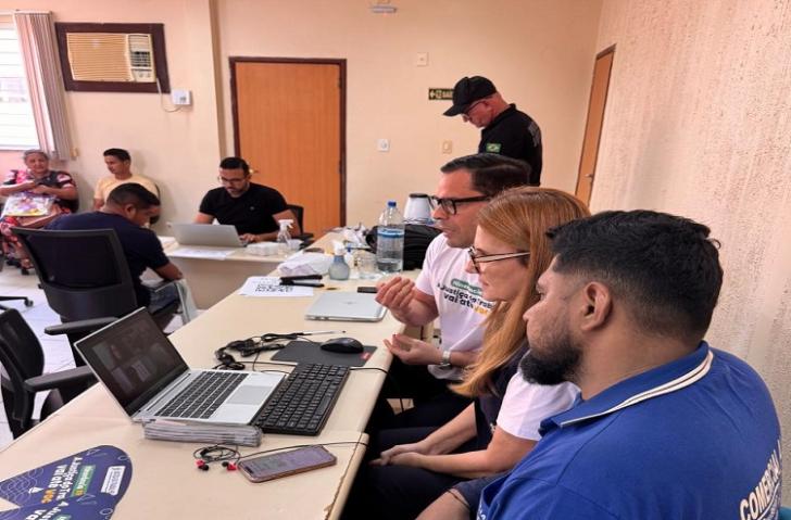 Fotografia de uma audiência trabalhista telepresencial, que reúne três pessoas presenciais e duas pelo virtual.