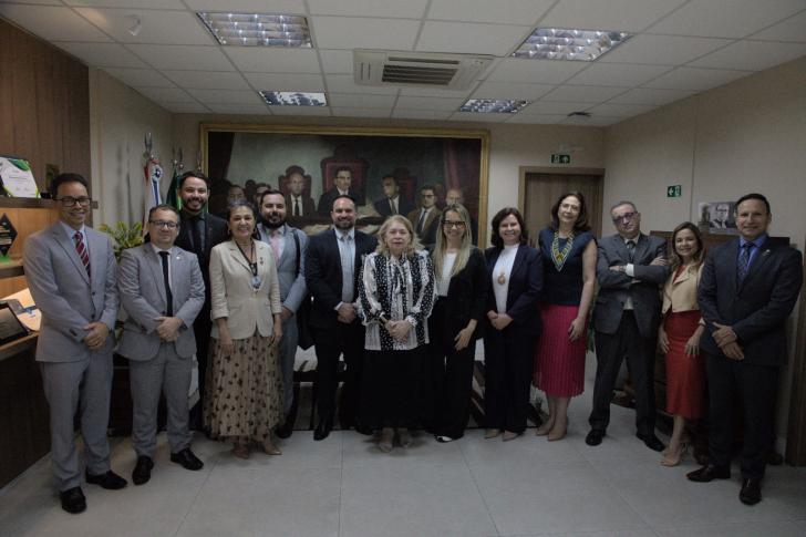 Foto de diversas pessoas, entre homens e mulheres, em espaço fechado.
