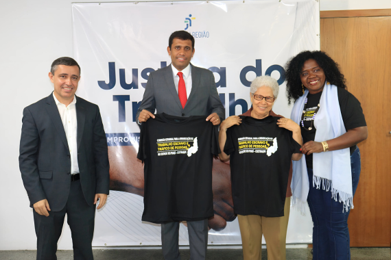 Fotografia com 2 homens e 2 mulheres, 2 deles estão segurando a camiseta em alusão ao Dia Nacional de Combate ao Trabalho Escravo.