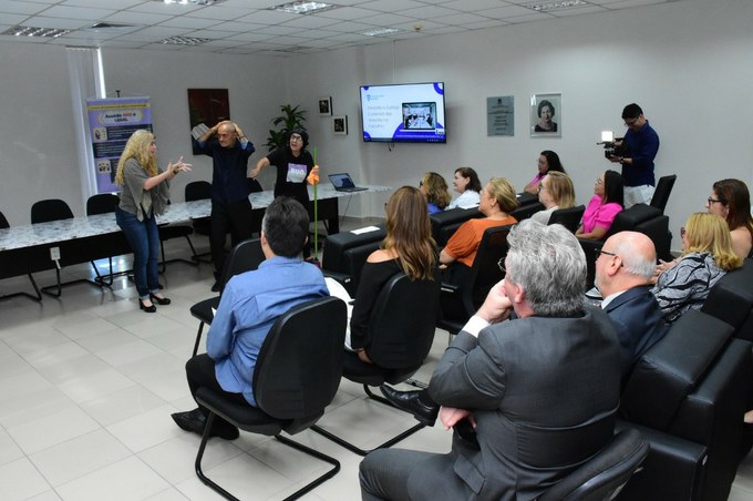 Fotografia com pessoas sentadas e 3 pessoas em pé palestrando no TRT-13 (PB).