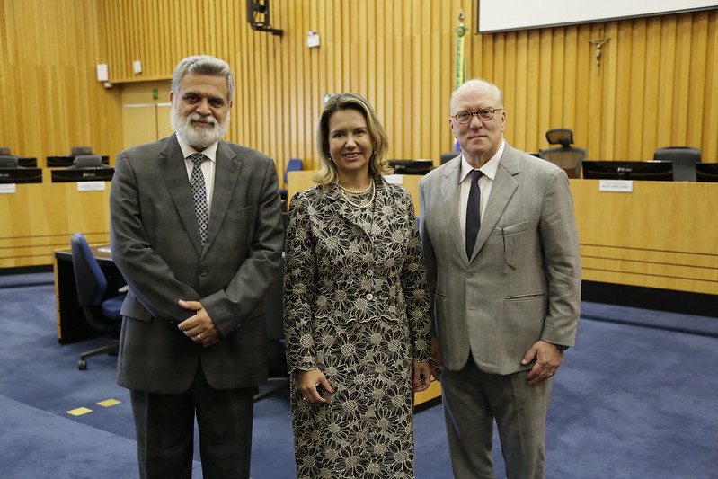 Ministro Lelio posado ao lado da desembargadora e do desembargador na sala de sessão. 