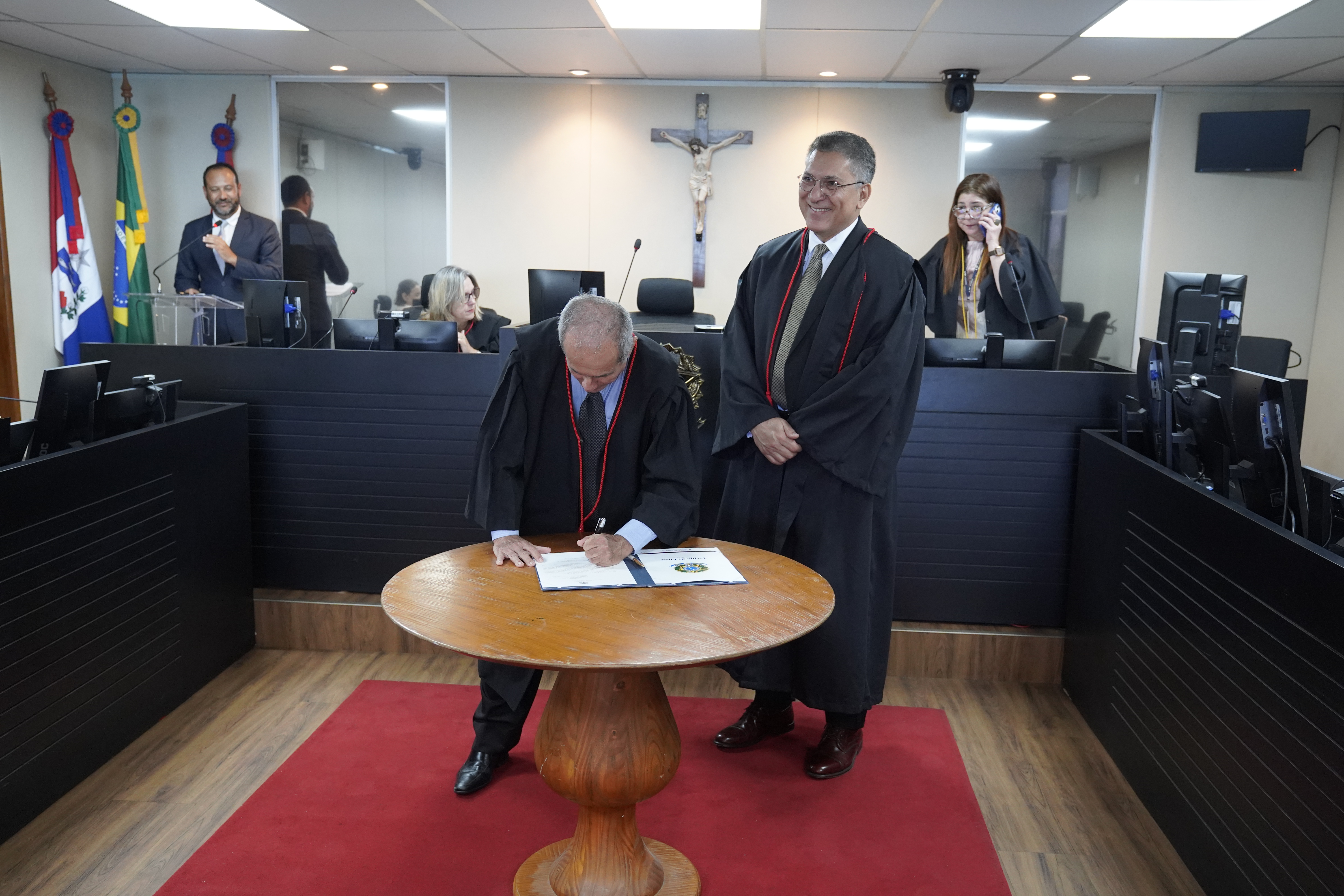 Fotografia dos novos gestores do TRT/AL; um deles está assinando um documento e o outro está posando para a foto.