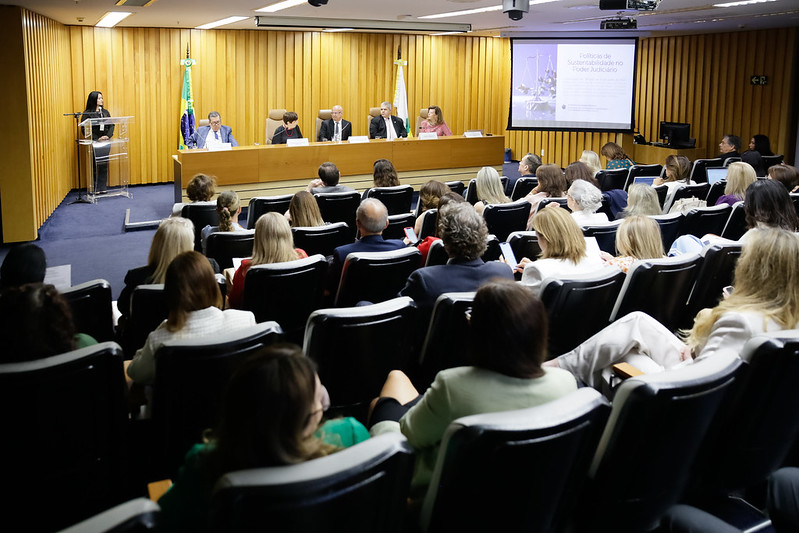 Foto do auditório onde foi realizado o Coleouv. Um auditório pequeno, mas com todas as cadeiras ocupadas na mesa e na plateia.