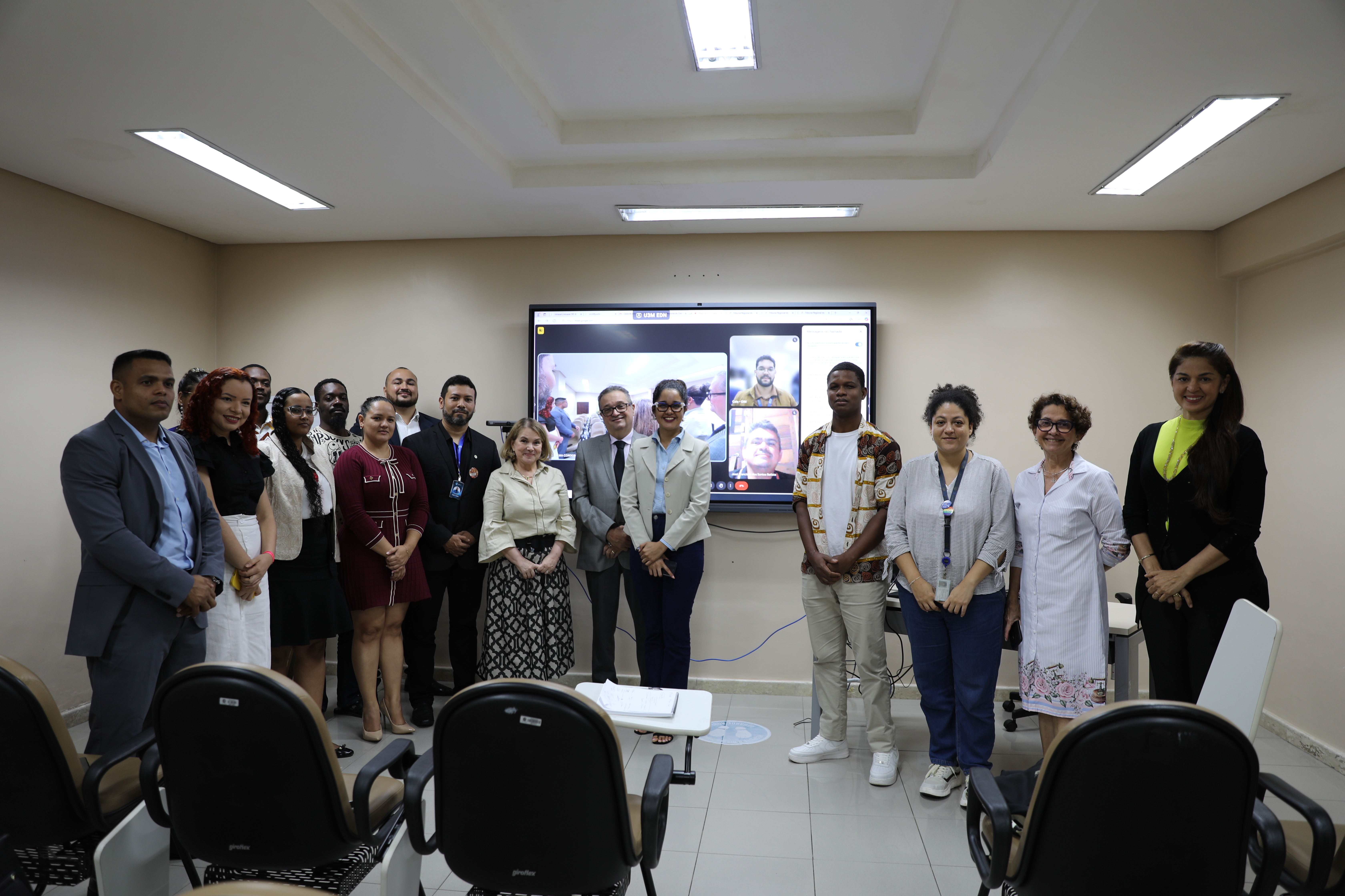 Fotografia colorida dos participantes da reunião, na foto todos estão em pé e sorrindo.
