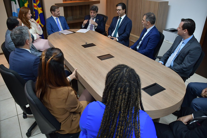 Mesa redonda com os participantes da assinatura do acordo prestando atenção nas palavras do ministro Caputo Bastos.