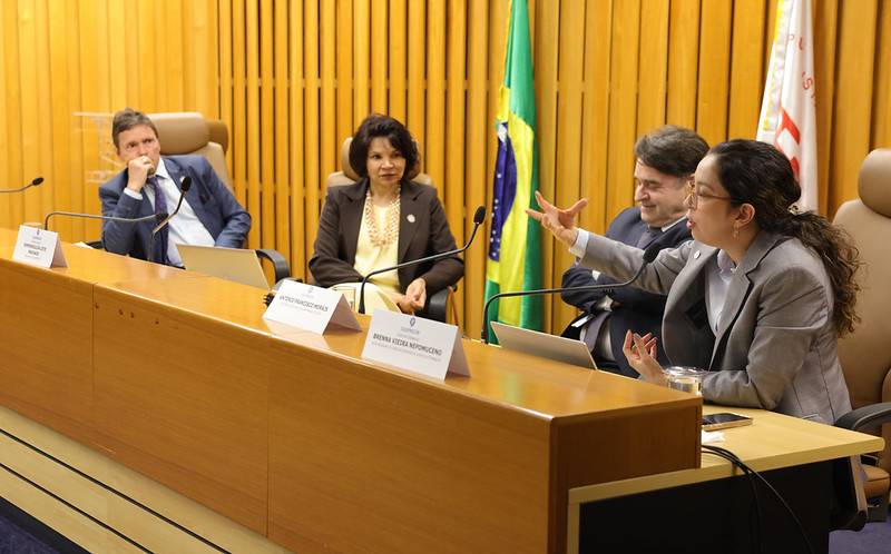 Foto da mesa do auditório com a juiza-auxliar do CSJT falando pra o público.