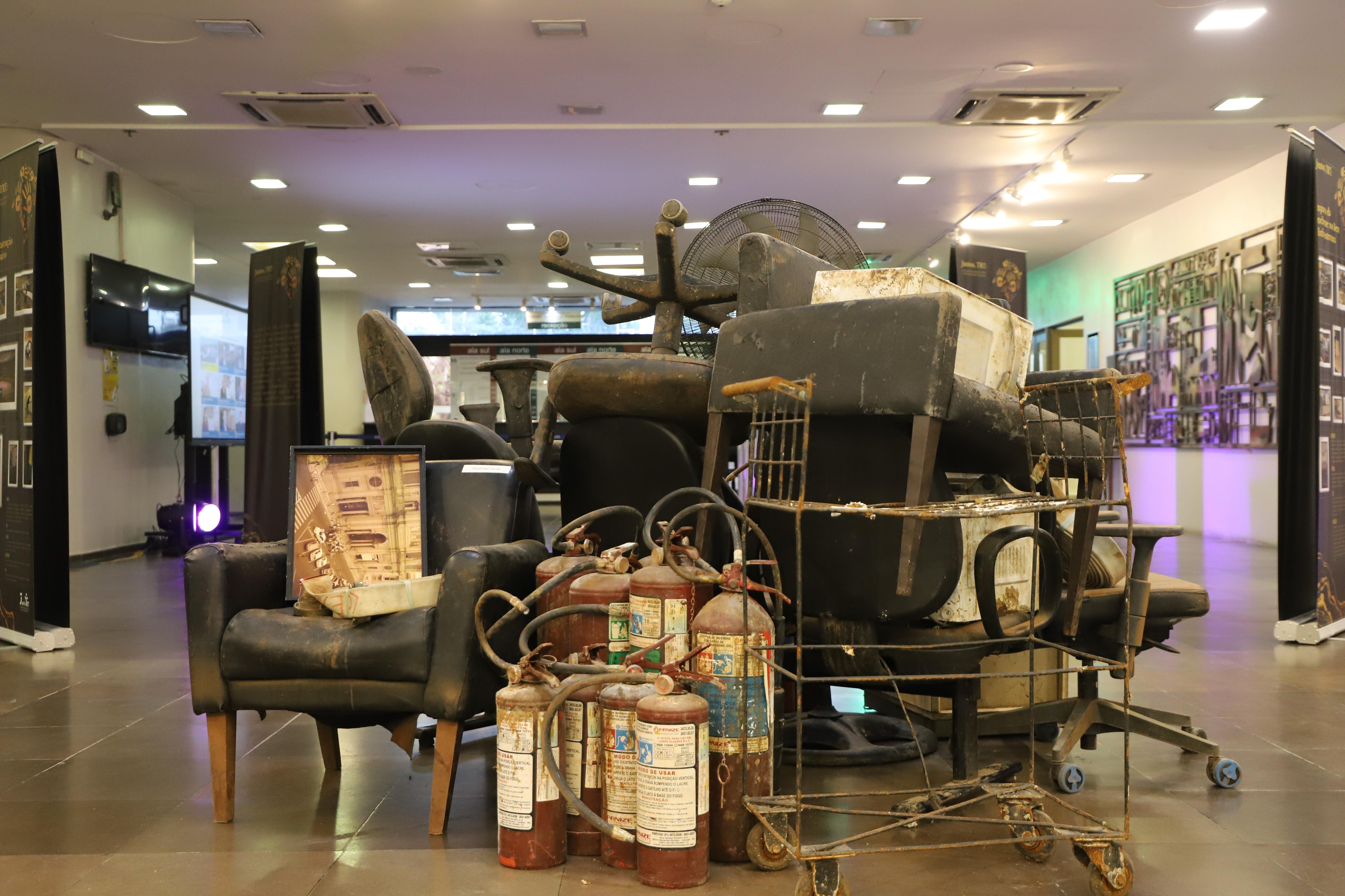 Fotografia de objetos em uma exposição, voltado à exposição sobre os impactos da enchente, no TRT-RS