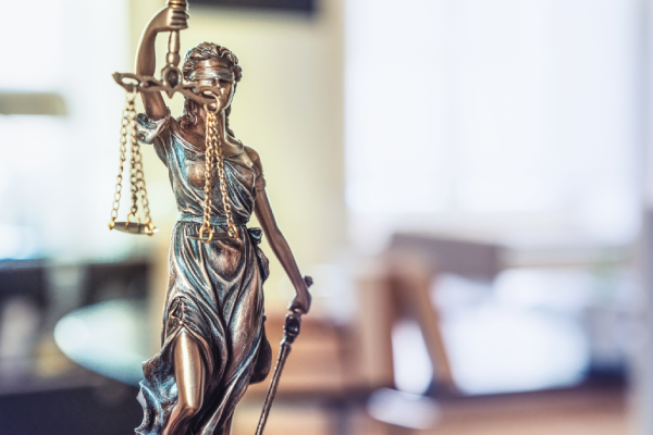 Foto de estatua da Justiça (mulher com olhos vendados segurança uma espada e uma balança).