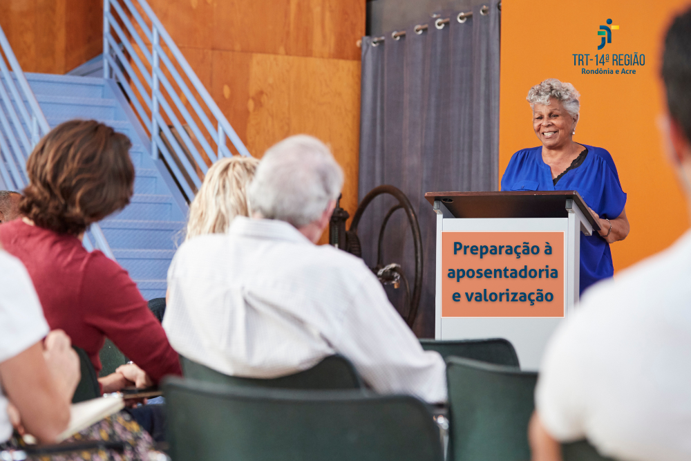 Imagem apresenta pessoas no público e uma mulher no palanque com a frase ''Preparação à aposentadoria e valorização''