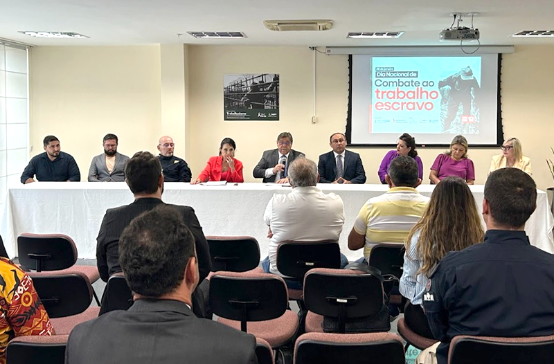 Fotografia com participantes do evento que aconteceu no TRT-21 (RN) e a mesa com o presidente do TRT-RN presente.