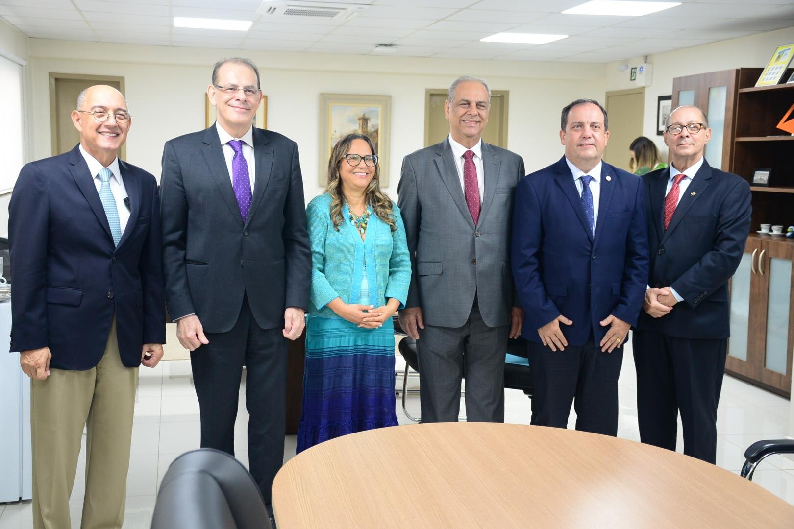 Fotografia com 6 pessoas, sendo 5 homens e 1 mulher, todos utilizando roupa social.