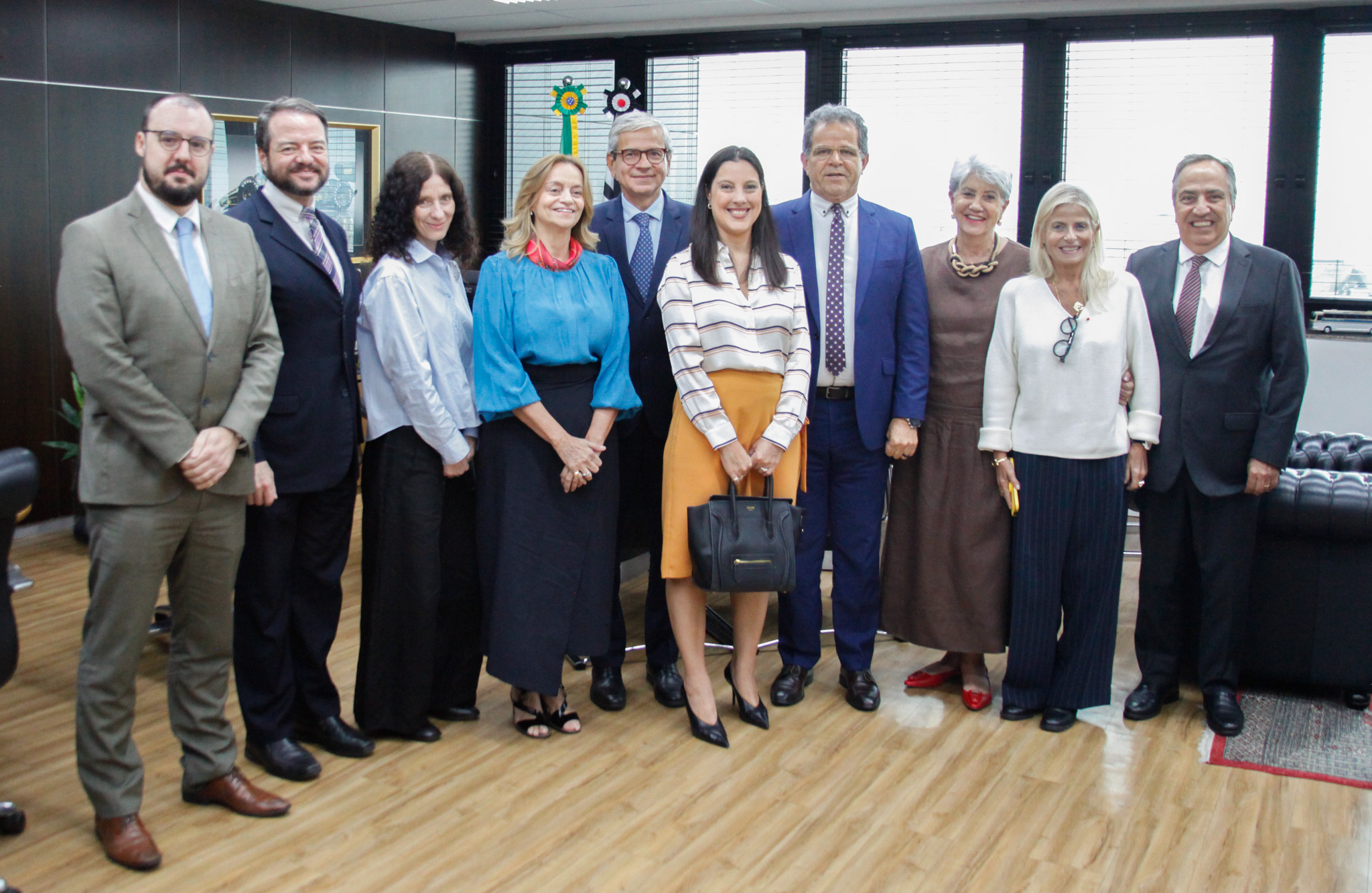 Fotografia com a presença de 10 pessoas, sendo 5 homens e 5 mulheres, todos usando roupa social.