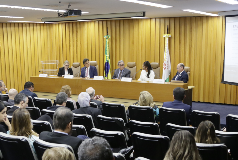 Foto do auditório com o presidente, o corregedor e a direção do Coleprecor na mesa. São duas mulheres, sendo uma a presidente, e um homem.