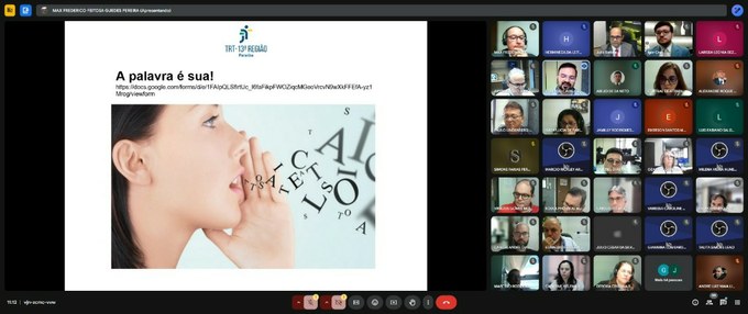 Captura de tela de uma videoconferência com diversos participantes. À esquerda, há um slide com a frase