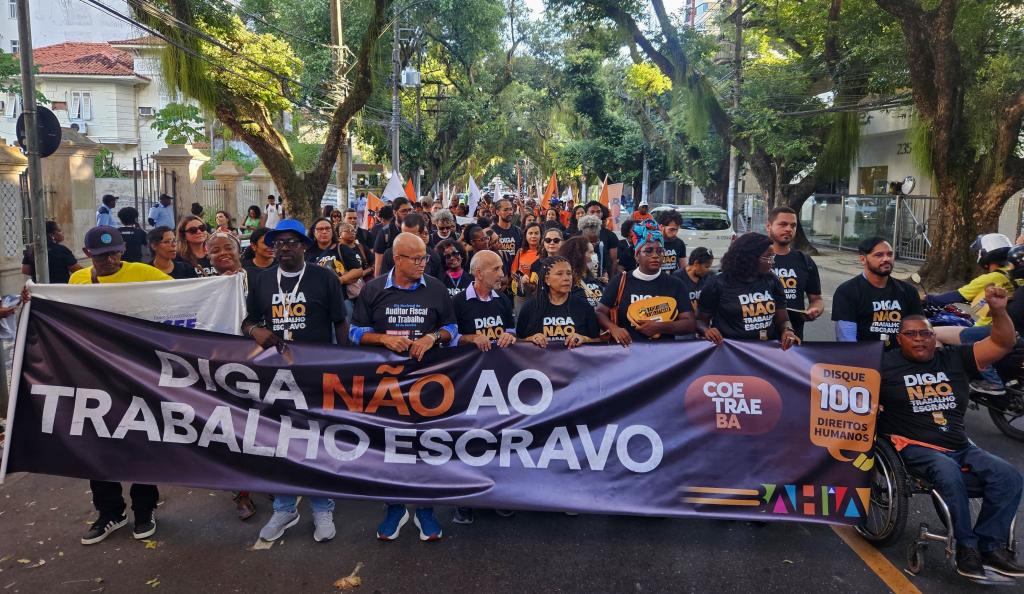 Fotografia com as pessoas que participaram da caminhada contra o trabalho escravo e algumas delas estão segurando o cartaz ''Diga Não ao Trabalho Escravo''.