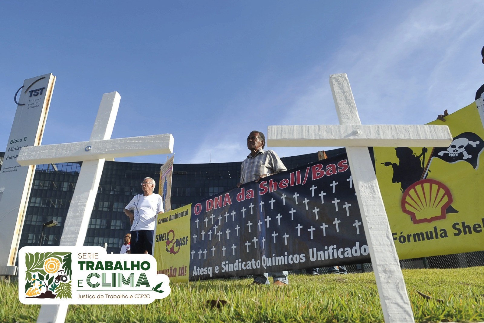 Manifestação em frente ao TST com cruzes enterradas no chão e faixa com texto 
