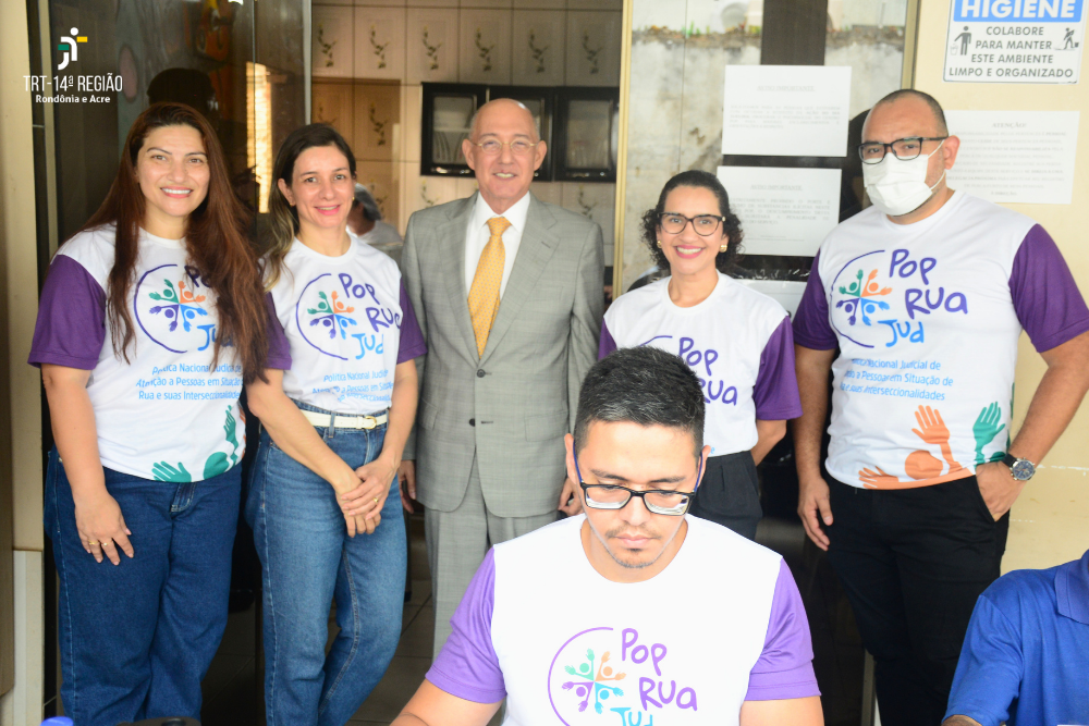 Fotografia com a presença de 6 pessoas, 3 mulheres e 3 homens, 5 deles usando a blusa do Pop Rua Jud e 1 com roupa social. 