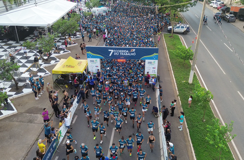 Fotografia de uma avenida recheada de pessoas referente a 7ª Corrida do Trabalho. 