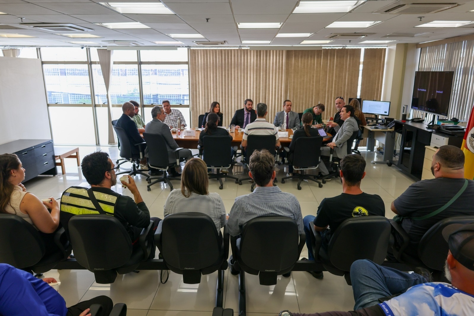 Mediação conduzida pelo desembargador Alexandre em 2025. Fotografia de uma mesa diretiva e algumas pessoas ao fundo sentadas acompanhando a reunião. 