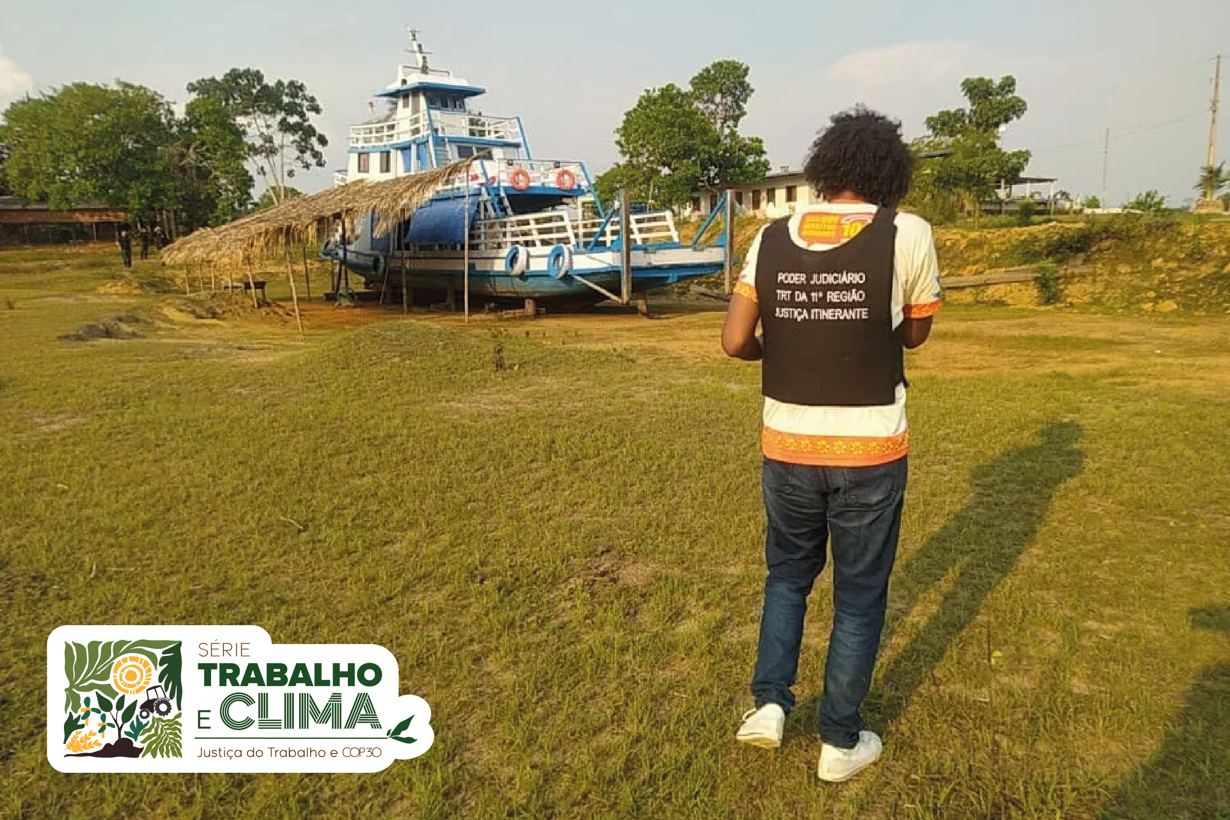 Servidor com colete da Justiça Itinerante diante de barco em terra firme