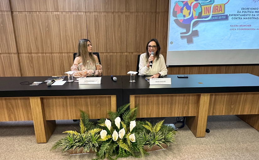 Foto de duas mulheres sentadas fazendo uma palestra.