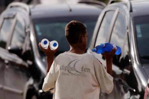 Foto de menino vendendo agua no trânsito. 